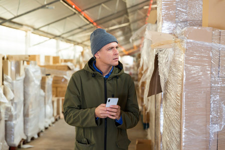 Store worker scans qr code on boxes using smartphone in warehouse shop