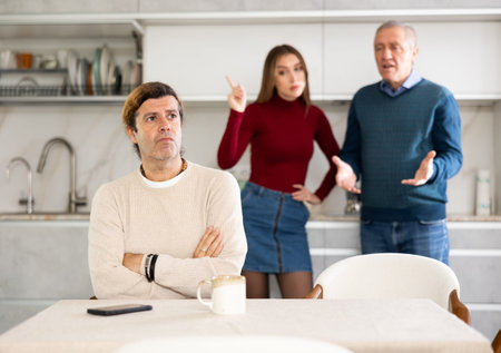 Adult man does not want to talk because of disagreements with his father and wife standing behind in...