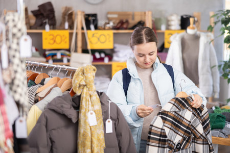 Teenage girl chooses coat in clothing storeの写真素材