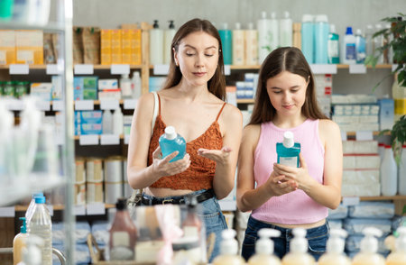 Mother and daughter in a summer dress choose mouthwash in pharmacyの写真素材