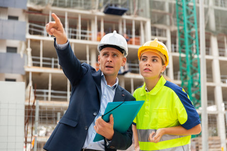 Male and female builders talking in construction site