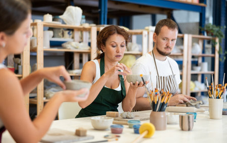 Three students in pottery workshop learn to create homemade plates and other utensils