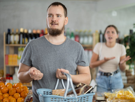 Young woman quarrels with man in grocery storeの写真素材