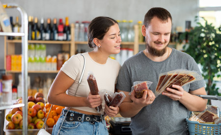 Spouses looking at hamon and dried sausage in storeの写真素材