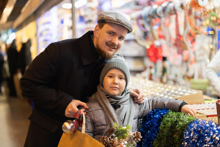 Son and father stand at the counter and choose decorations for the Christmas treeの写真素材