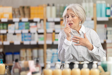 Elderly woman with cough at pharmacyの写真素材