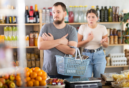 Young woman quarrels with man in grocery storeの写真素材