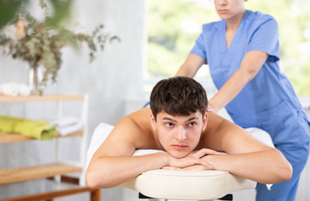 Masseuse doing back massage to young guyの写真素材