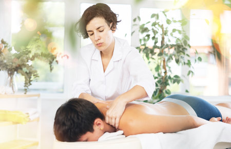 Relaxing happy man getting back massage in spa centerの写真素材