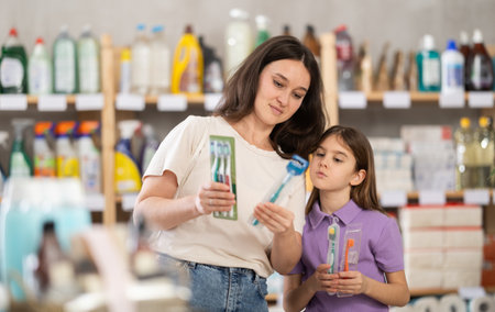 Little dughter and mother choose toothbrushes together in supermarketの写真素材