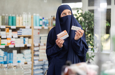 Young Muslim woman customer choosing pills in box in drugstoreの写真素材