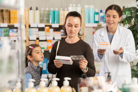 woman with a child buys medicines at a pharmacy with a pharmacistの写真素材