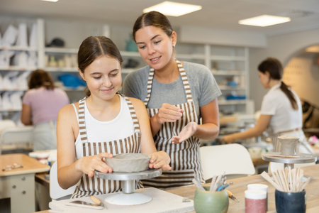 Female teacher explains to student how to make ceramics