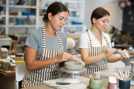 Girls perform work on molding blanks from raw clay and painting staining themの写真素材