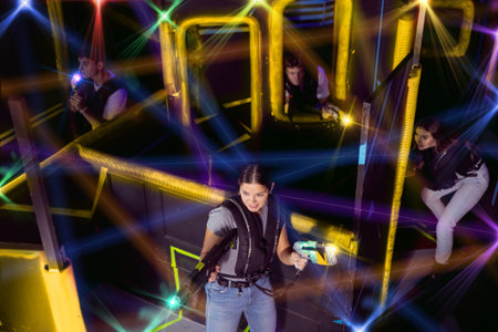 Four people having fun playing lasertag ducking behind cover in maze of lasertag arenaの写真素材