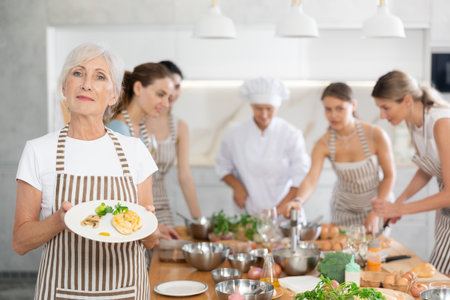 Elderly woman posing with prepared chicken dishの写真素材