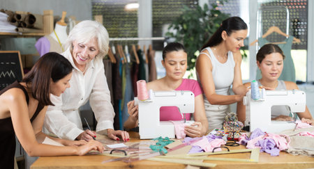 Group of busy women sewing and drawing with teacher at dressmaking coursesの写真素材