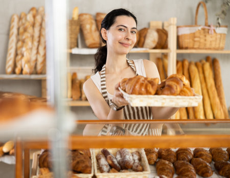Young woman seller with basket of croissantsの写真素材