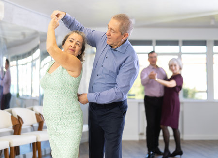 Elderly man and elderly woman dance waltzの写真素材