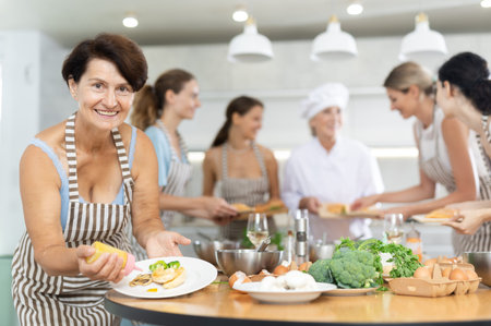 Elderly woman pouring sauce into dish at master class