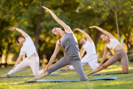 Woman performing yoga asanas during group session in parkの写真素材