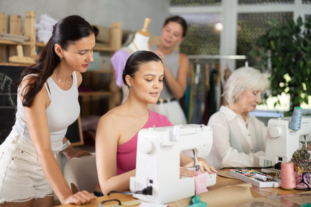 Young woman stitching at machine during group sewing courseの写真素材