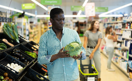 Man choosing cabbage in supermarketの写真素材