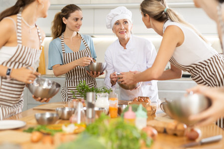 Mature female cook holding bowl and whiskの写真素材