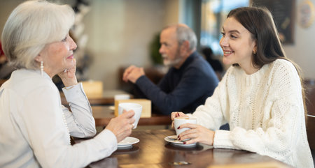 Girl in cafe sits near senior female companion, has nice conversation