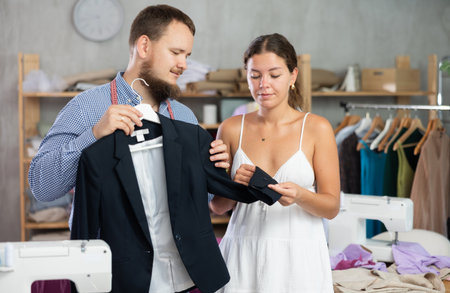 Male dressmaker showing finished jacket to young girlの写真素材