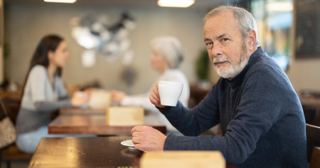 Elderly man drinks coffee in cafeの写真素材