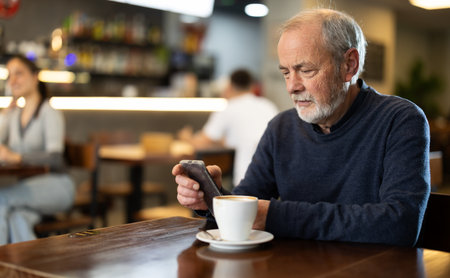 Elderly man drinks coffee in cafe interiorの写真素材