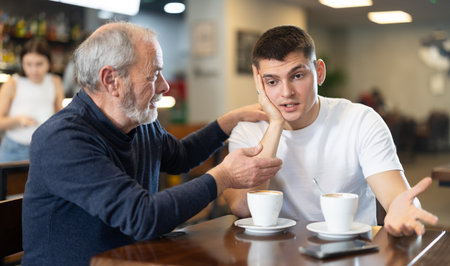 Meeting at cafe, elderly man comforts his sonの写真素材