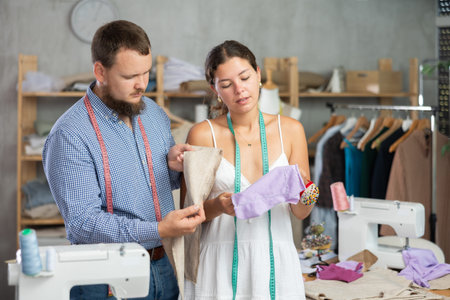 Young female dressmaker discussing textile with manの写真素材