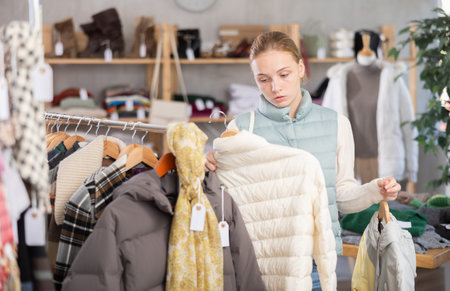 Teen girl choosing down jacket in clothing store