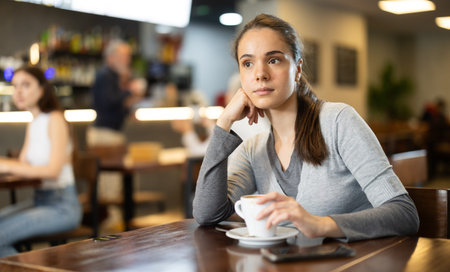 Pretty girl drinks coffee in cafe interior
