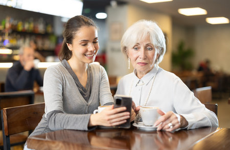 Young woman showing elderly woman photos on mobile