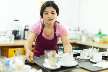 Cafe waitress clears dirty dishes from tables and takes them to the kitchen for washing.の写真素材