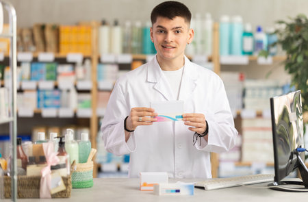 Young pharmacist holding boxes of pills
