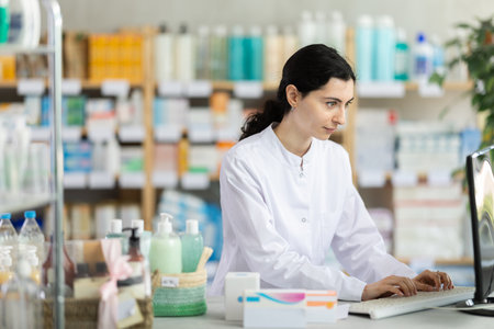 Female pharmacist working at a computer in a pharmacyの写真素材