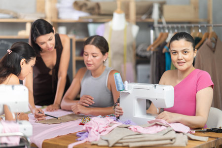 Young woman stitching at machine during group sewing course