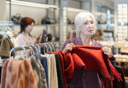 Eldery woman chooses scarf in accessories storeの写真素材