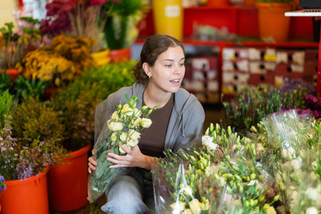 Girl salesman takes out bunch of eustoma from showcase, creates bouquetsの写真素材