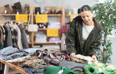 Adult woman chooses sweater in clothing store