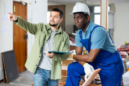 Worker and owner building discuss construction plan inside building under constructionの写真素材