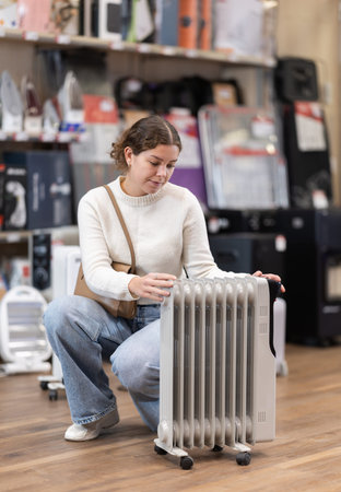 Woman buying oil heater in storeの写真素材