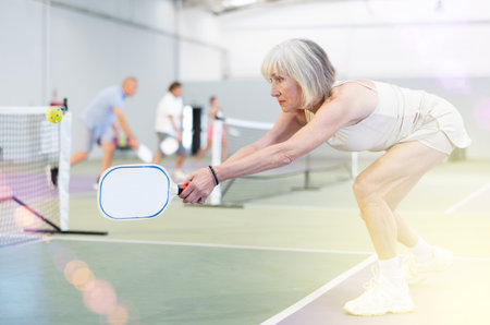 Mature woman playing doubles pickleball game, healthy lifestyle conceptの写真素材