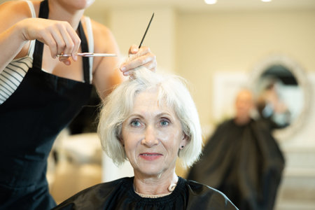 Hairdresser is listening to wishes of mature woman about her hairstyle