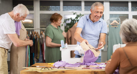 Man discussing pattern with female classmate during sewing course for older adultsの写真素材