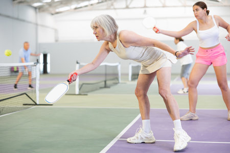 Sporty senior woman playing pickleball on indoor courtの写真素材